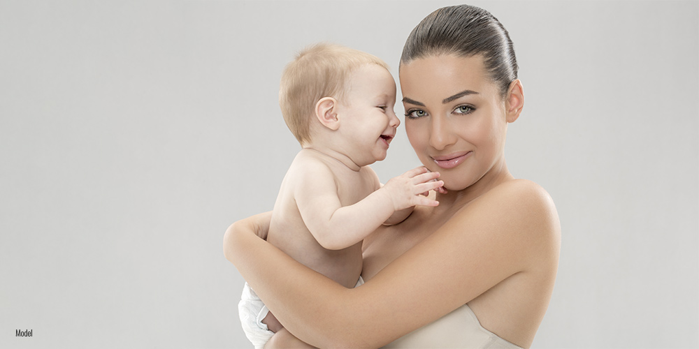 Mom holding her baby in her arm on grey background